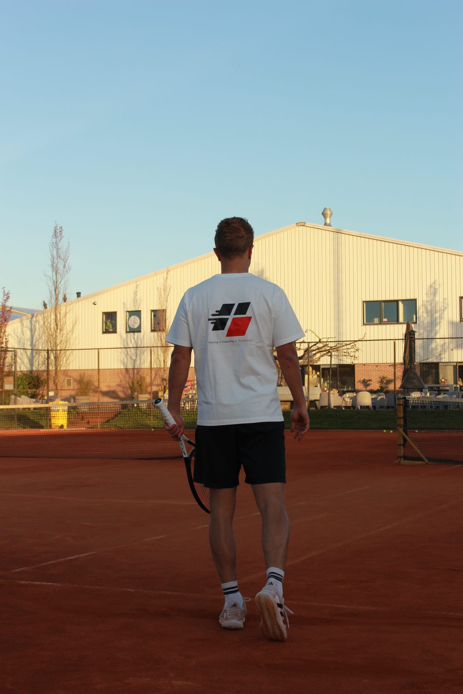 Gijs Feij loopt over de gravelbaan, shirt met Training, Coaching, Psychology